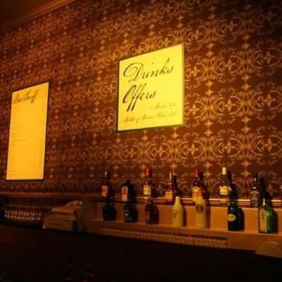 Bottles and signage for a Bar with Brunel fabric wall linings as wall papee