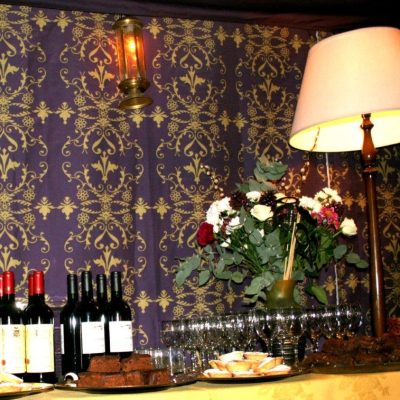 A bar set with wine bottles and a standard lamp in front of patterned wall linings