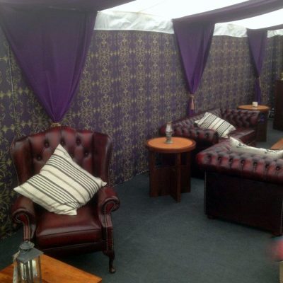 A marquee lined with Brunel marquee wall linings and purple overlay filled with Chesterfield furniture