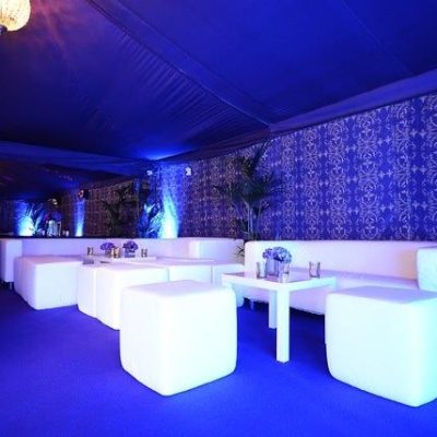 Nightclub lighting shining on Brunel marquee walls and white furniture in a themed party tent