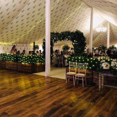 A marquee dancefloor with bespoke printed linings overhead and bright lighting
