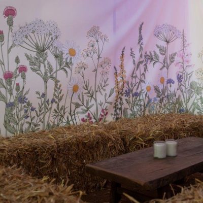 Botanical wall linings hanging on a marquee wall with hay bales set in front of them
