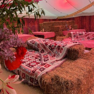 A pile of hay styled with a crochet blanket in front of wood plank marquee wall linings