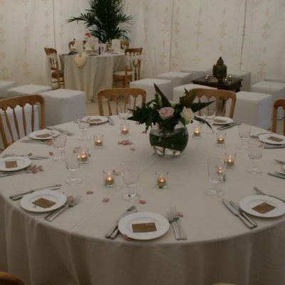 A dining table set with a white cloth with palm trees and a Jasmine marquee lining
