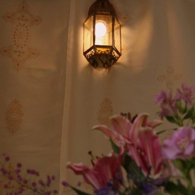 A single light hangs above a floral display inside a wedding marquee