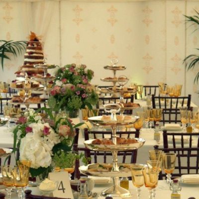 A marquee set up for afternoon tea with cake stands and a Jasmine wal lining on the wall