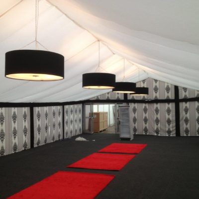A Marquee interior with Rococo wall linings a white flat ceiling lining and red rugs on the black floor