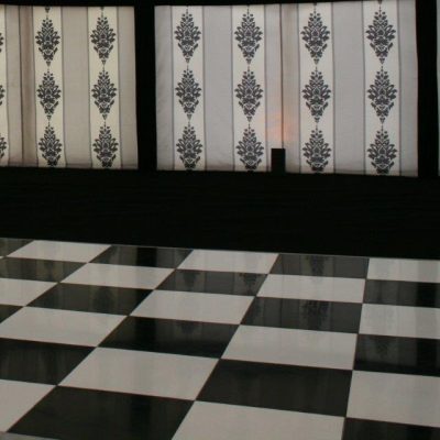 A marque with black white and grey marquee linings black carpet and a chequerboard black and white dance floor