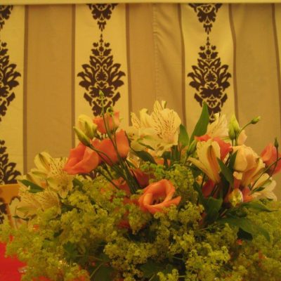 A bouquet of flowers and foliage sits on a table in front of Rococo marquee wall linings