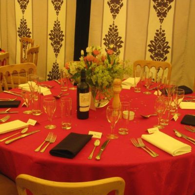 A marquee with Rococo marquee wall linings and a table set with red cloth and black and white napkins