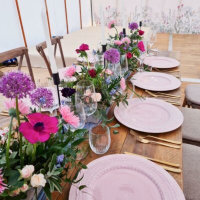 Botanical marquee wall linings hang behind a top table at a wedding breakfast