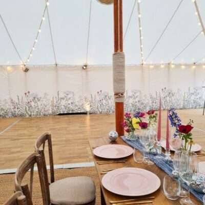 Botanical marquee wall linings line the walls of a pretty traditional pole marquee