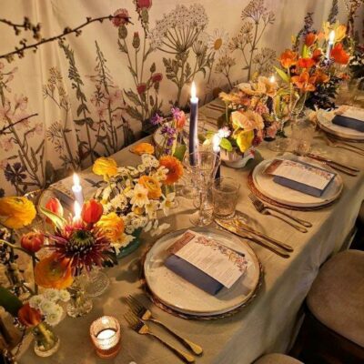 Botanical wall linings behind a styled table with candles lit at an exhibition