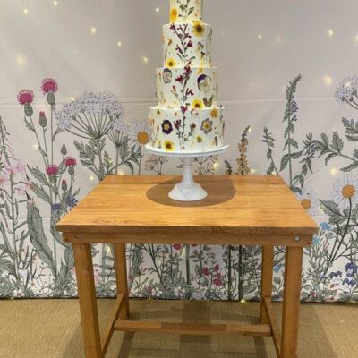 Floral Wedding cake on a table with botanical wall drape behind